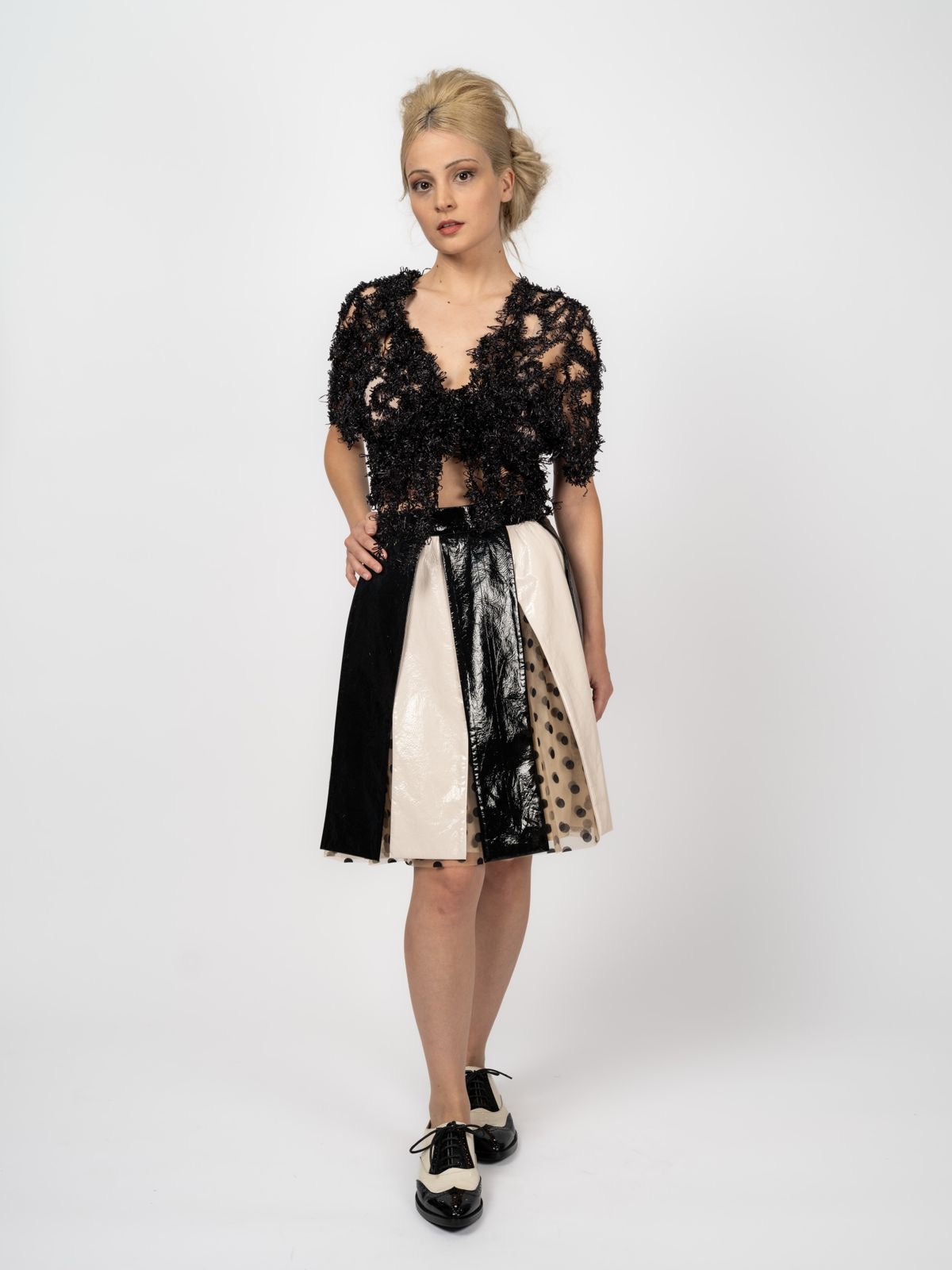 Transparentes schwarzes Top aus Fantasie-Strick mit V-Ausschnitt, kombiniert mit Rock in Schwarz und Creme, von Maya Seyferth