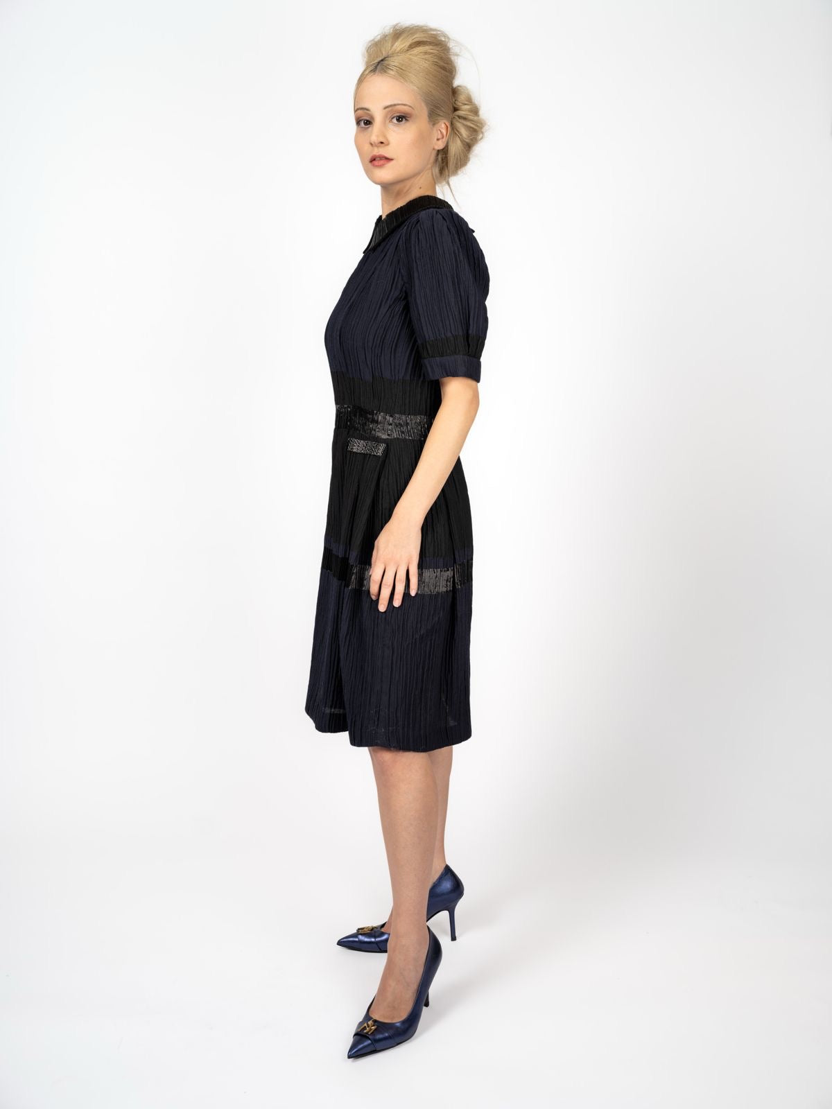 Knielanges Kleid in Marineblau und Schwarz mit Crinkle-Struktur, Bubikragen und glänzenden Bändern, dazu marineblaue Pumps, von Maya Seyferth