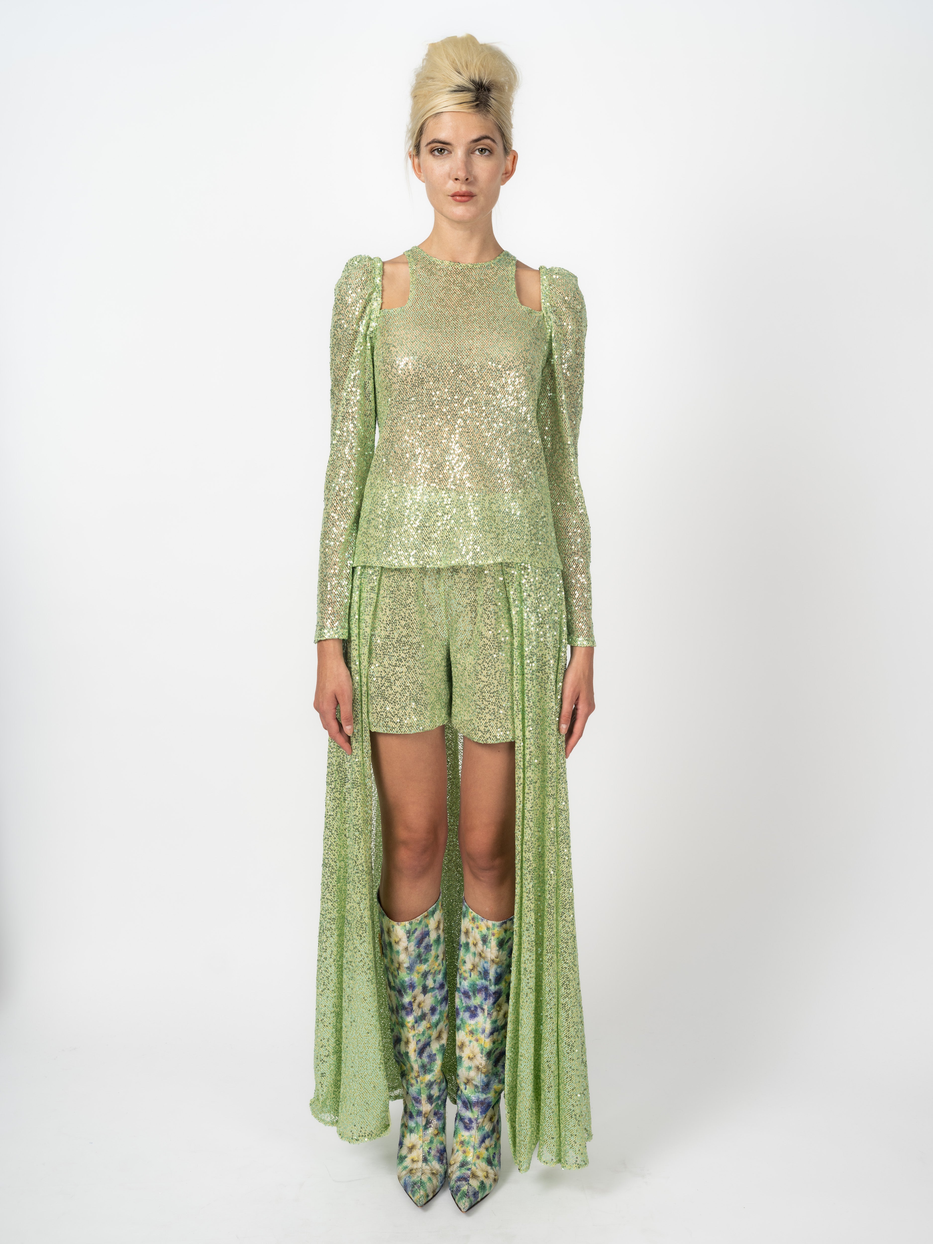 Couture-Outfit in Hellgrün: Pailletten-Top mit Schulter-Cut-outs und Shorts mit bodenlanger Schleppe, dazu Stiefel mit Blütenmotiv, von Maya Seyferth