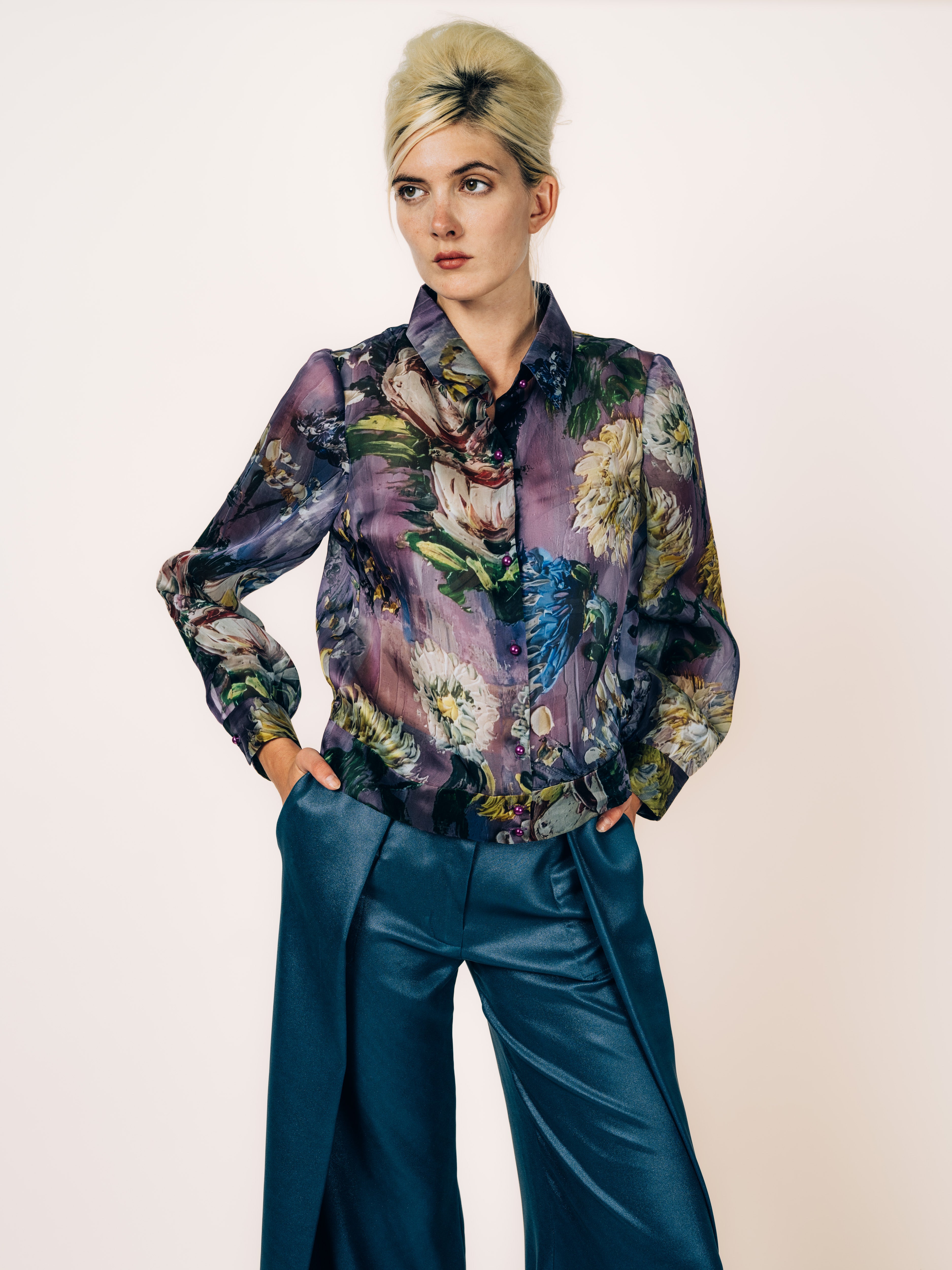 Organza-Bluse in Violett mit künstlerischem Blütenmotiv und Perlknöpfen, kombiniert mit rauchblauer Seidenhose, von Maya Seyferth
