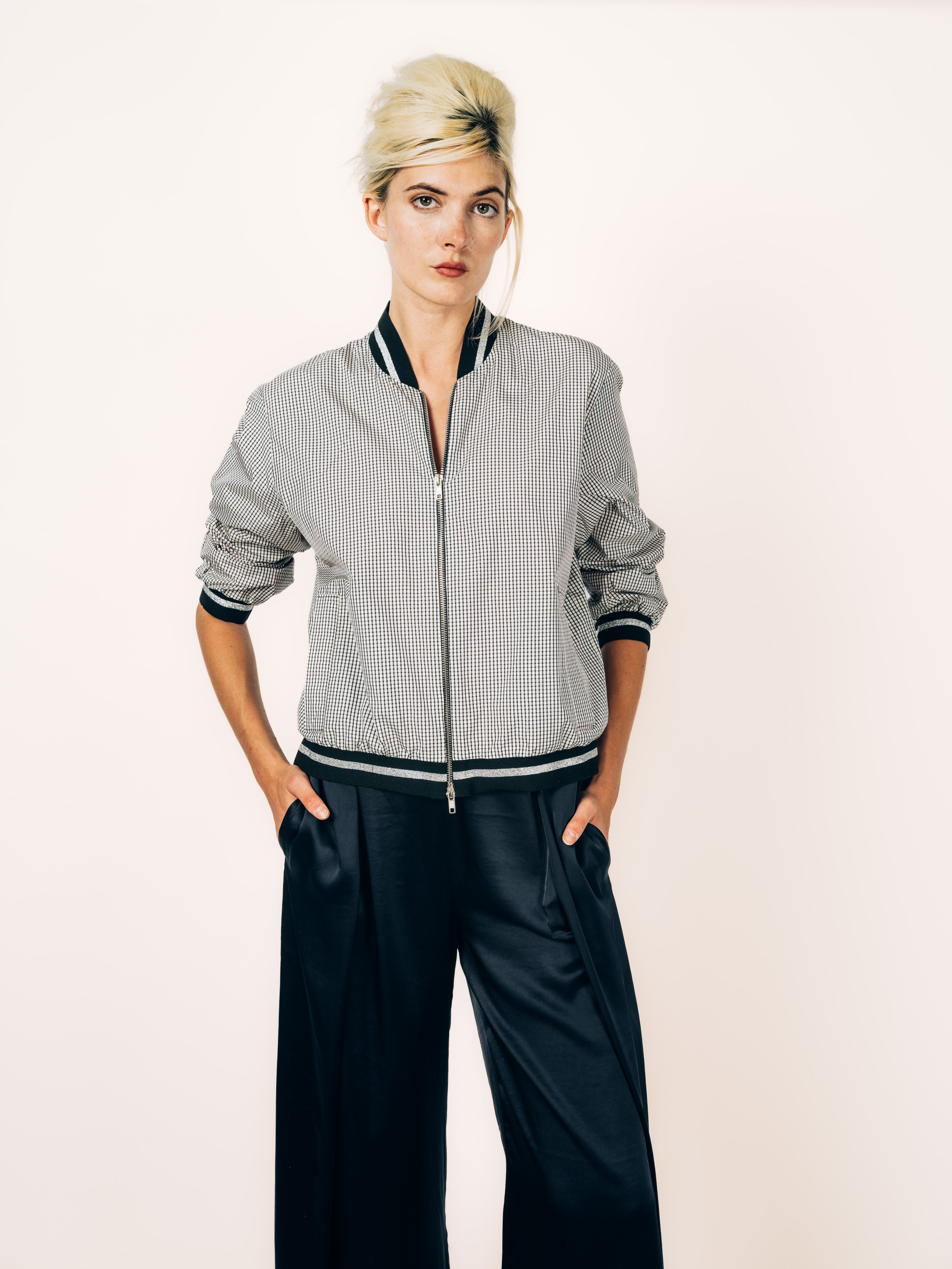 Bomberjacke Karo in Schwarz und Weiss mit Silberstreifen an Kragen und Bündchen, kombiniert mit schwarzer Seidenhose, von Maya Seyferth