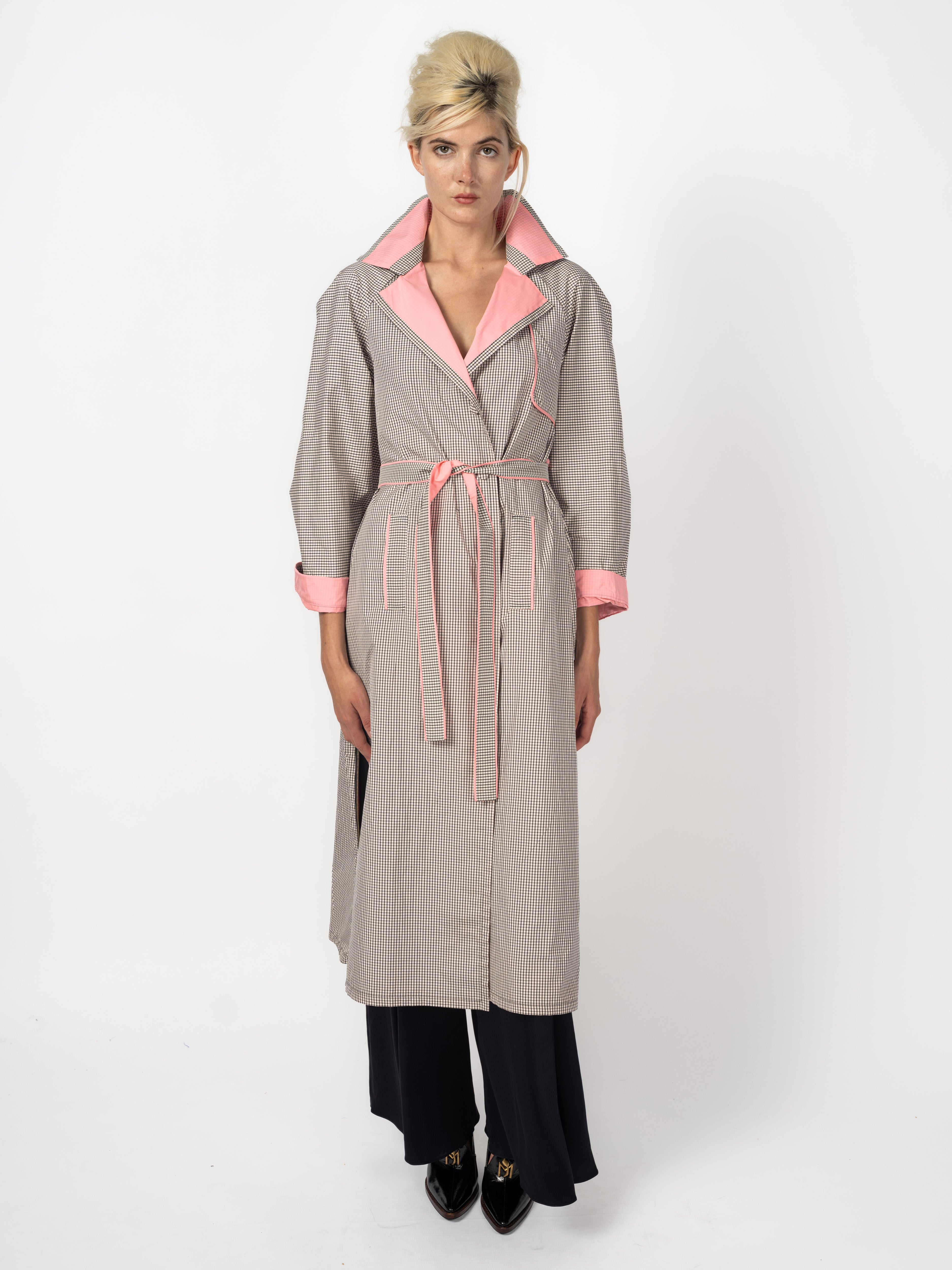 Trenchcoat im Karomuster Schwarz und Weiss mit rosa Revers, Paspeln und Bindegürtel, kombiniert mit schwarzer Seidenhose, von Maya Seyferth