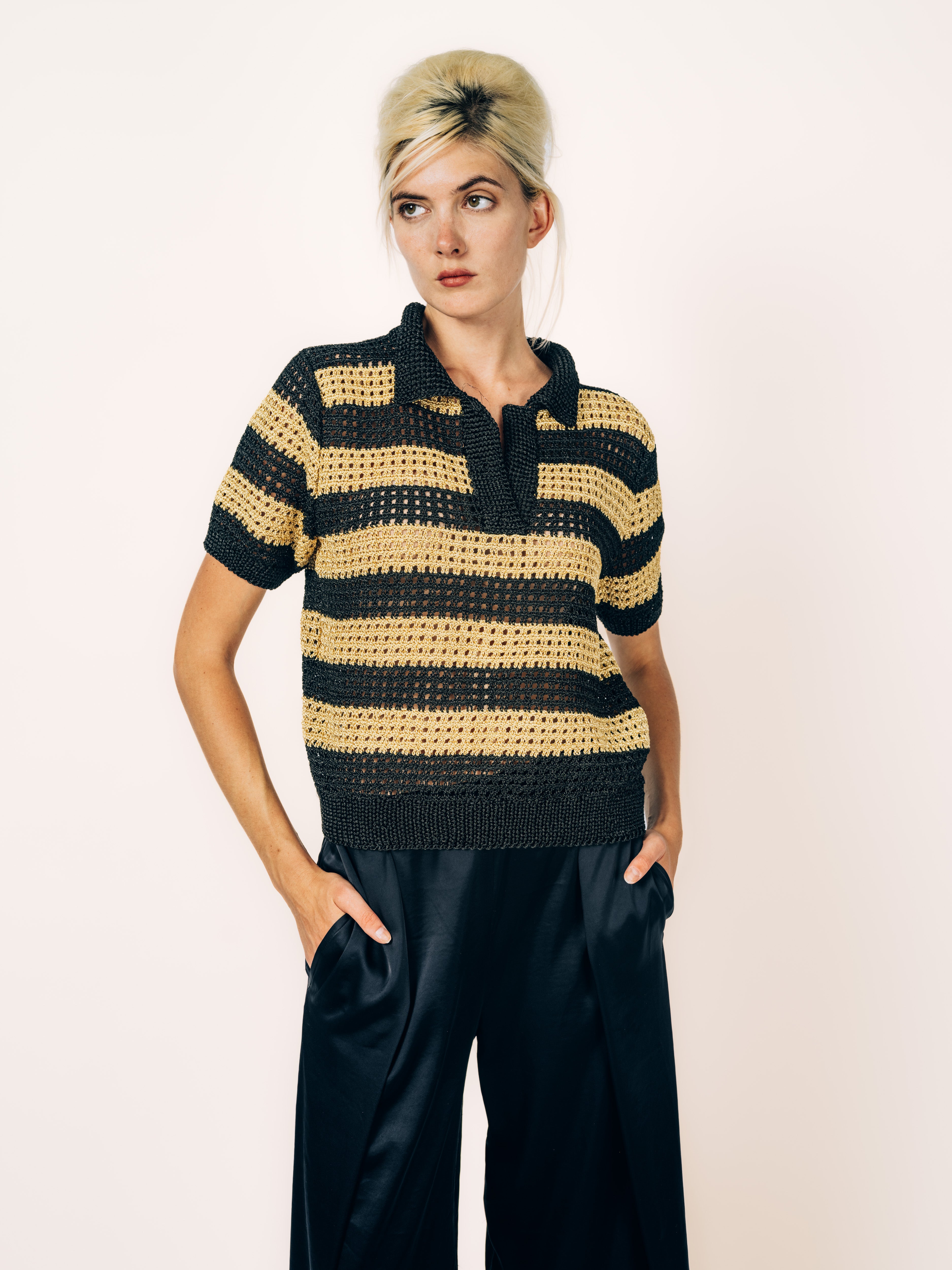 Handgestrickter Kurzarm-Pullover mit Polokragen und Streifen in Schwarz und Gold, kombiniert mit schwarzer Seidenhose, von Maya Seyferth