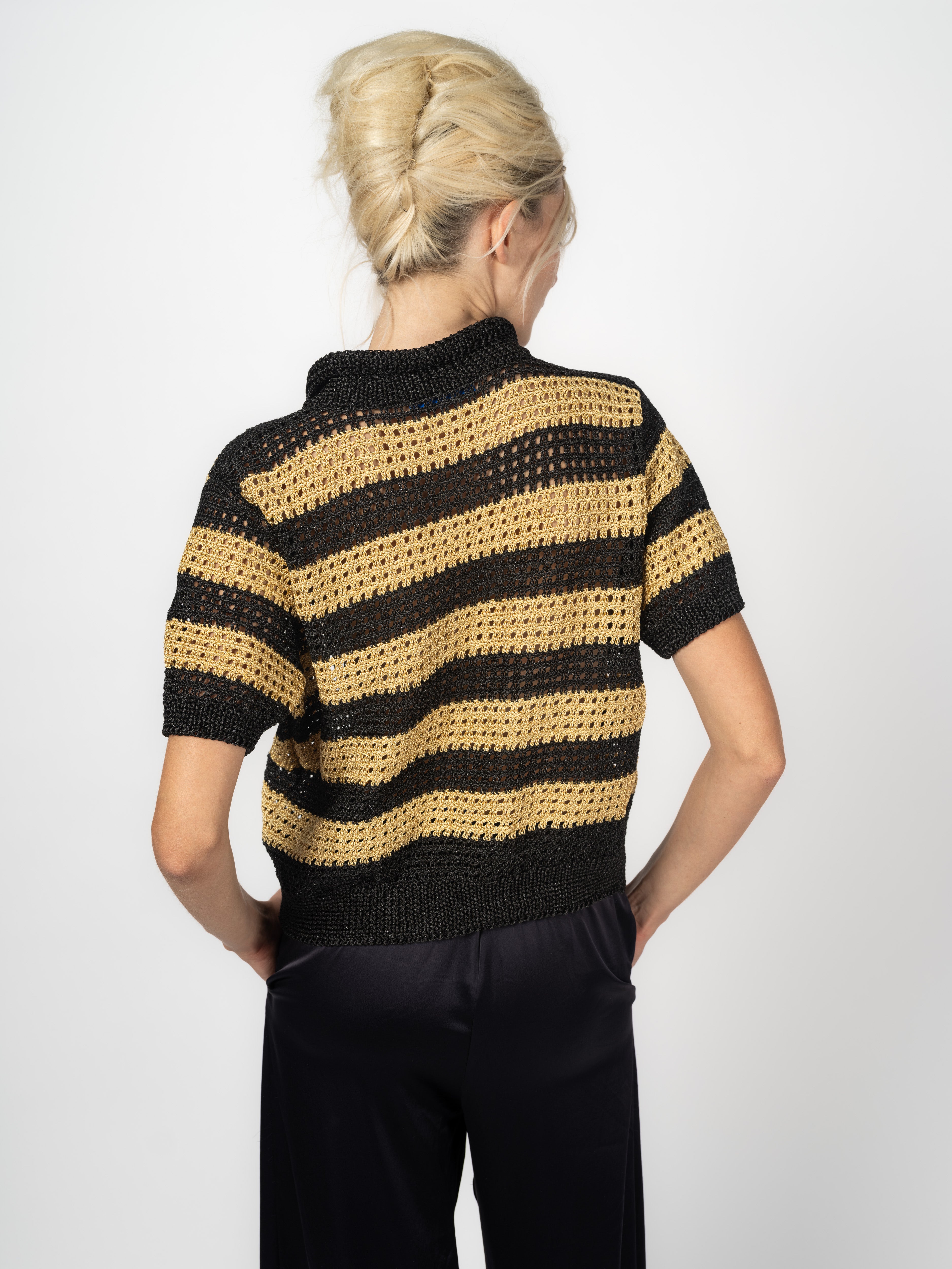 Handgestrickter Kurzarm-Pullover mit Polokragen und Streifen in Schwarz und Gold, kombiniert mit schwarzer Seidenhose, von Maya Seyferth