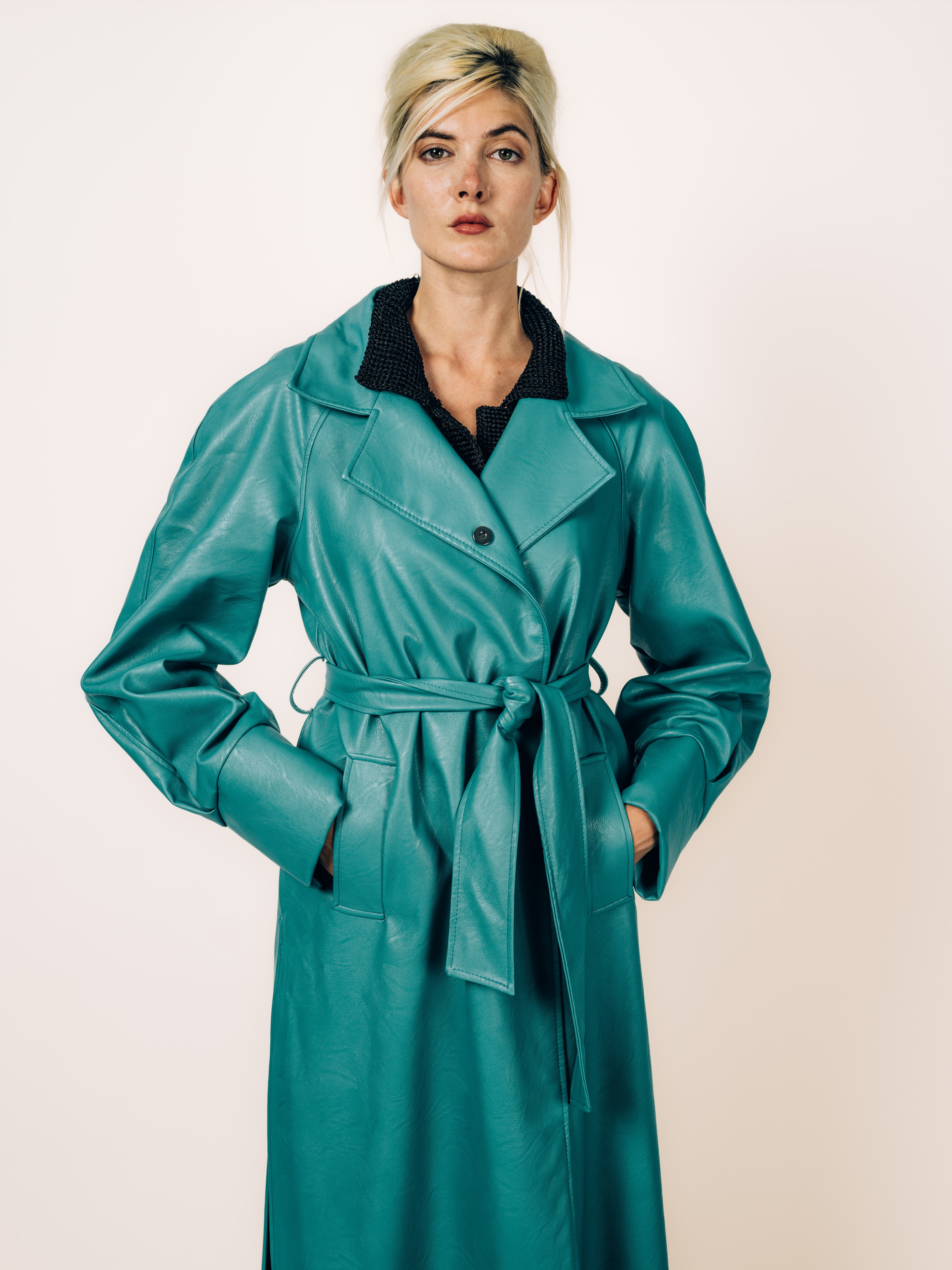 Oversized Trenchcoat in Türkis aus veganem Leder mit Bindegürtel, getragen über schwarzer weiter Hose, von Maya Seyferth