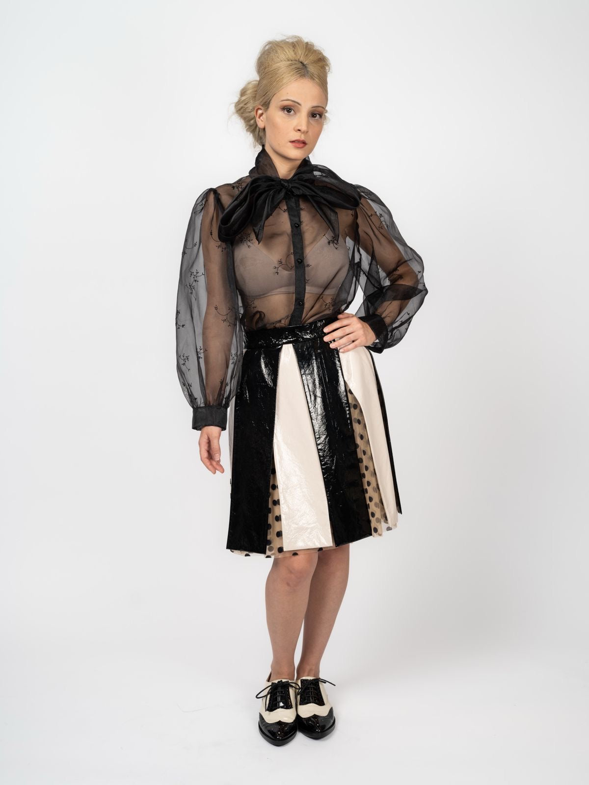 Schwarze Chiffon-Schluppenbluse mit feiner Stickerei und Rock in Schwarz und Creme mit gepunkteten Tülleinsätzen, dazu zweifarbige Schnürschuhe, von Maya Seyferth
